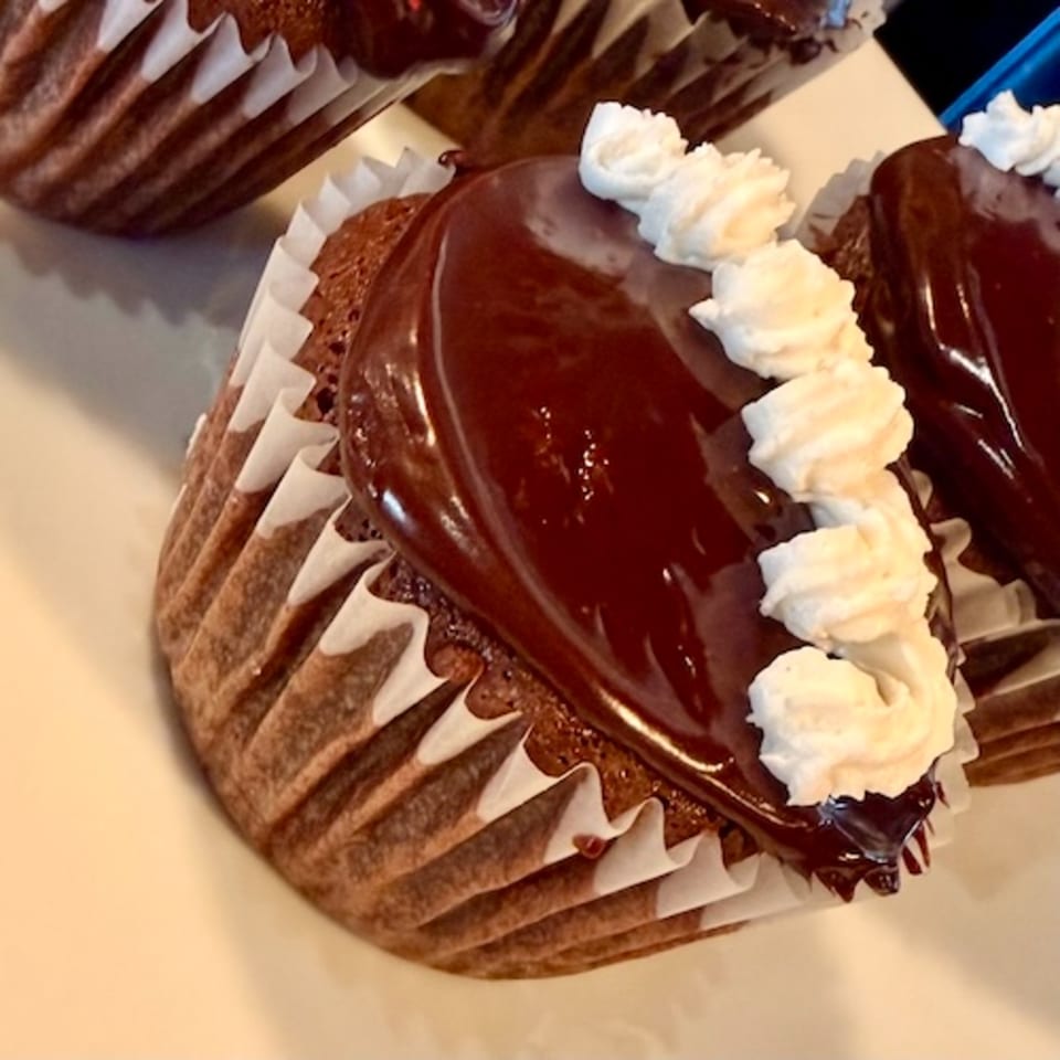Chocolate-covered waffle topped with whipped cream and chocolate drizzle on a plate.