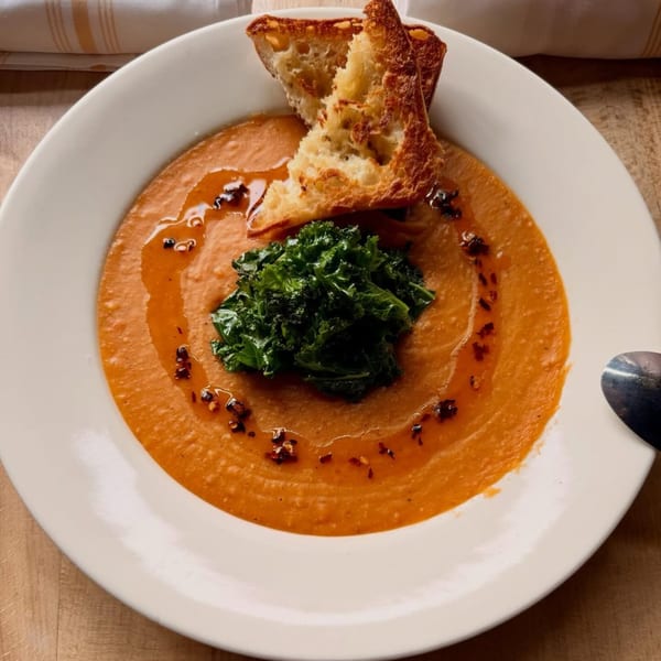 Vegan tomato soup with a dollop of kale, chili oil, and two pieces of toasted bread.